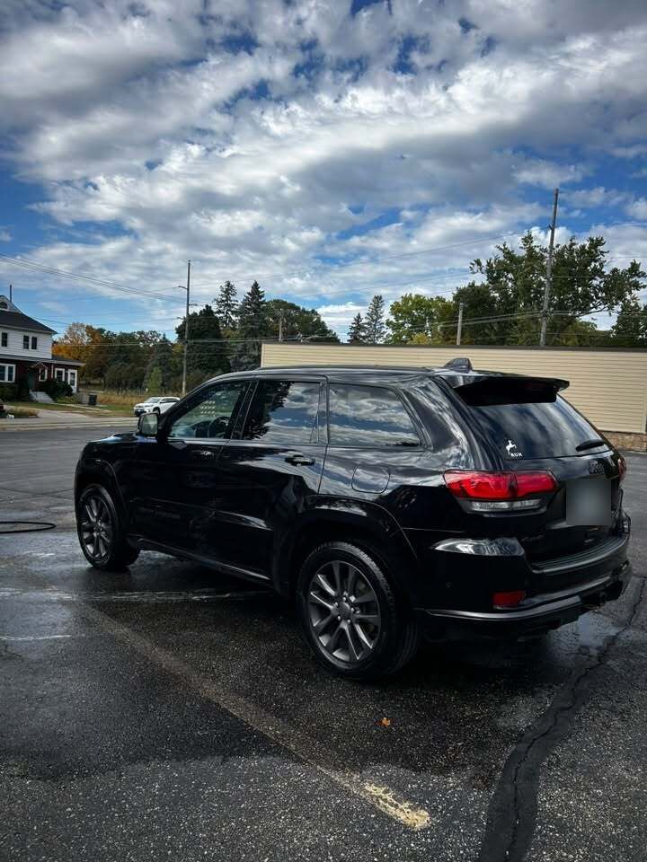 Black Jeep Grand Cherokee with a glossy finish reflecting the clouds